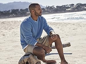 Man on beach sitting on drift wood