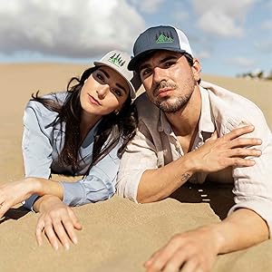 a men and women wearing a trucker hat relax by the beach in our snapback hat