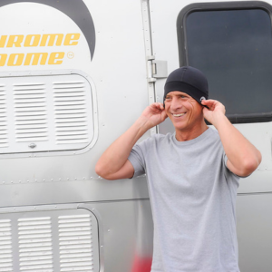 Smiling man pulling a Chrome Dome Cap snug over his ears.